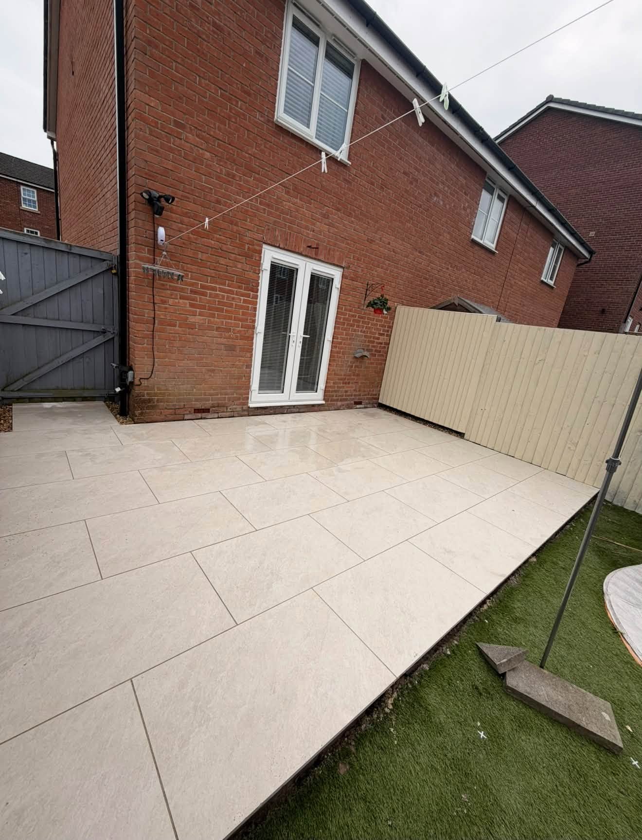 Finished pale porcelain patio beside a brick house